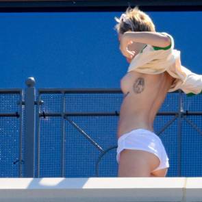 Miley Cyrus puts on a shirt over naked boobs